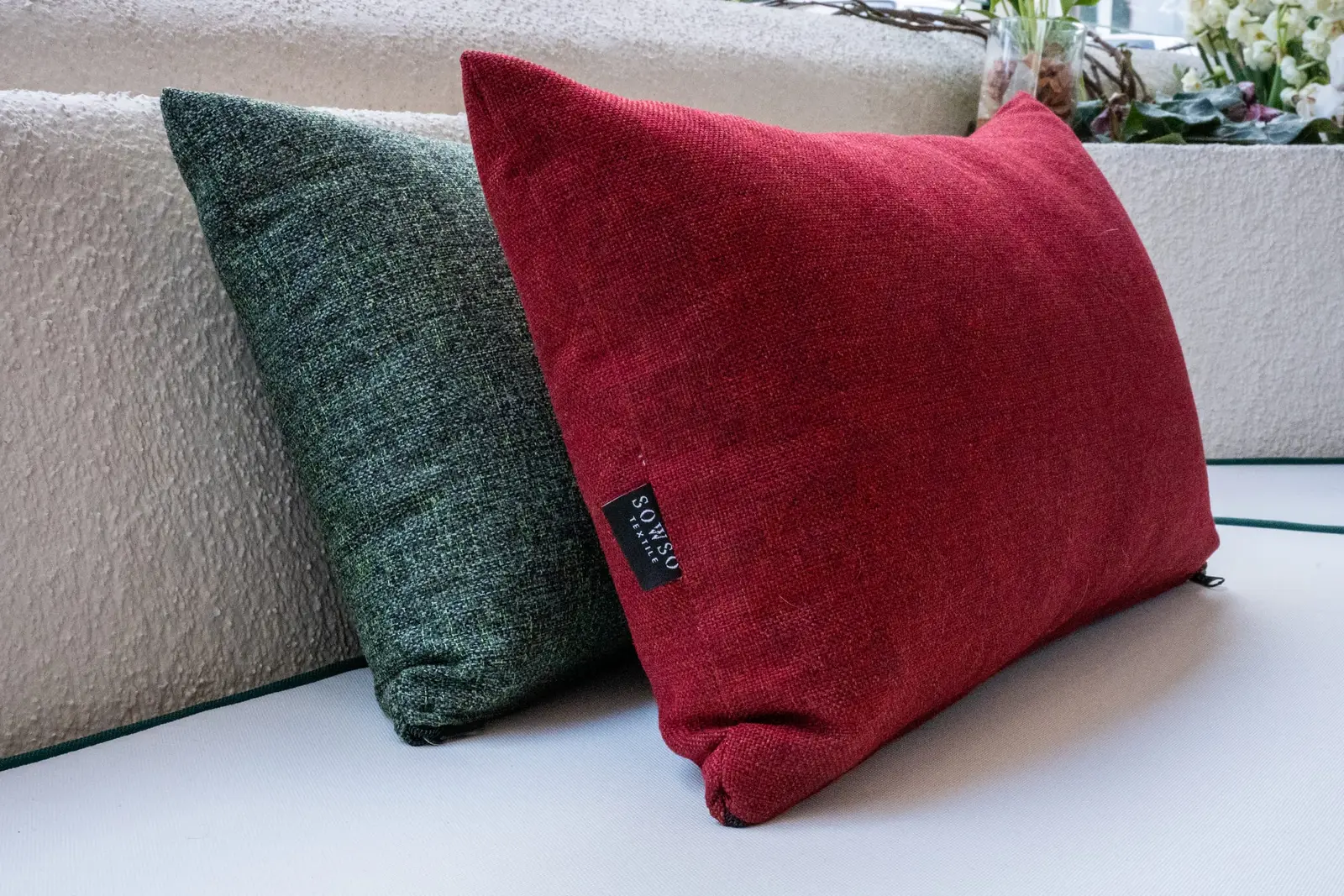 Krem minder üzerinde yeşil ve kırmızı yastıklar, SOWSO Textile dokuma etiketi görünür